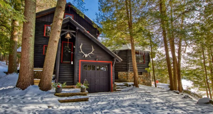 A lakefront Adirondack home in the early spring; snow is still on the ground, but the sky is sunny