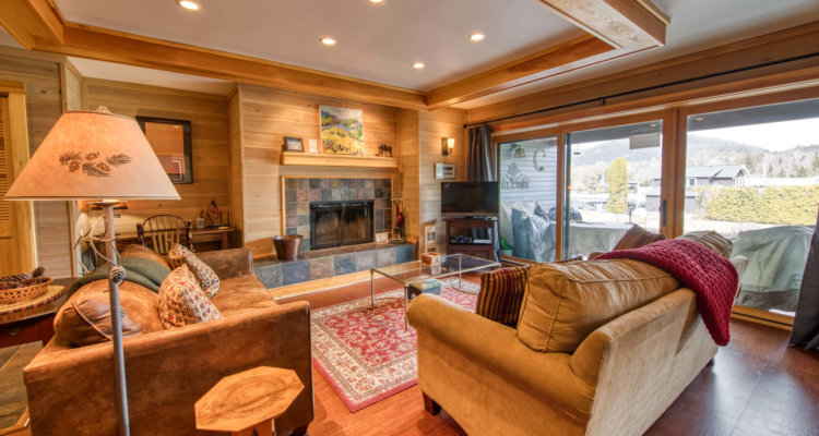 A contemporary-looking interior of a condo with a stone-lined fireplace and all wood flooring and walls