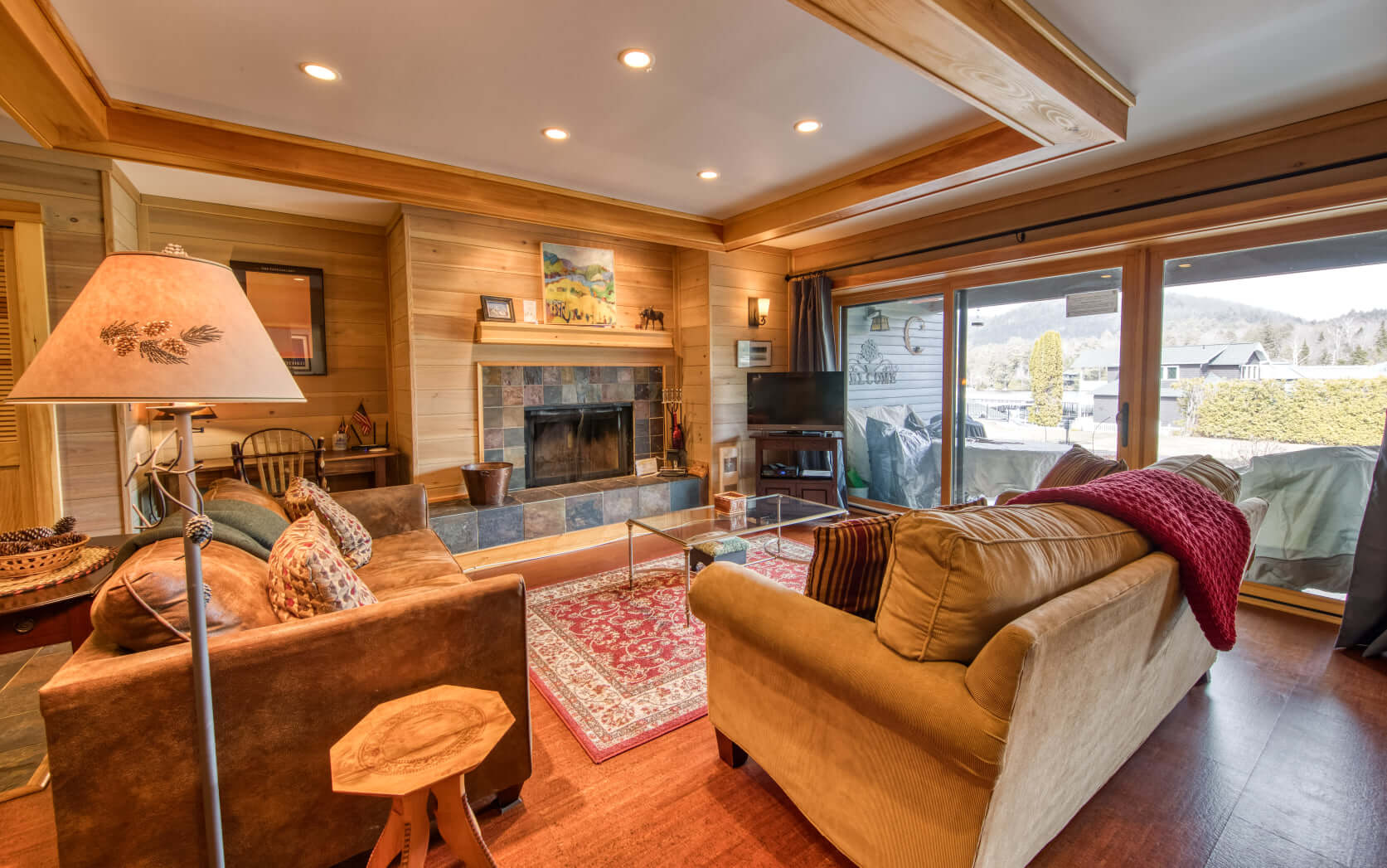 A contemporary-looking interior of a condo with a stone-lined fireplace and all wood flooring and walls