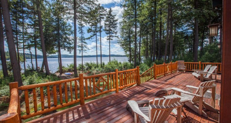 Adirondack reclining chairs are positioned on the beautiful wood porch to catch the warm afternoon sun