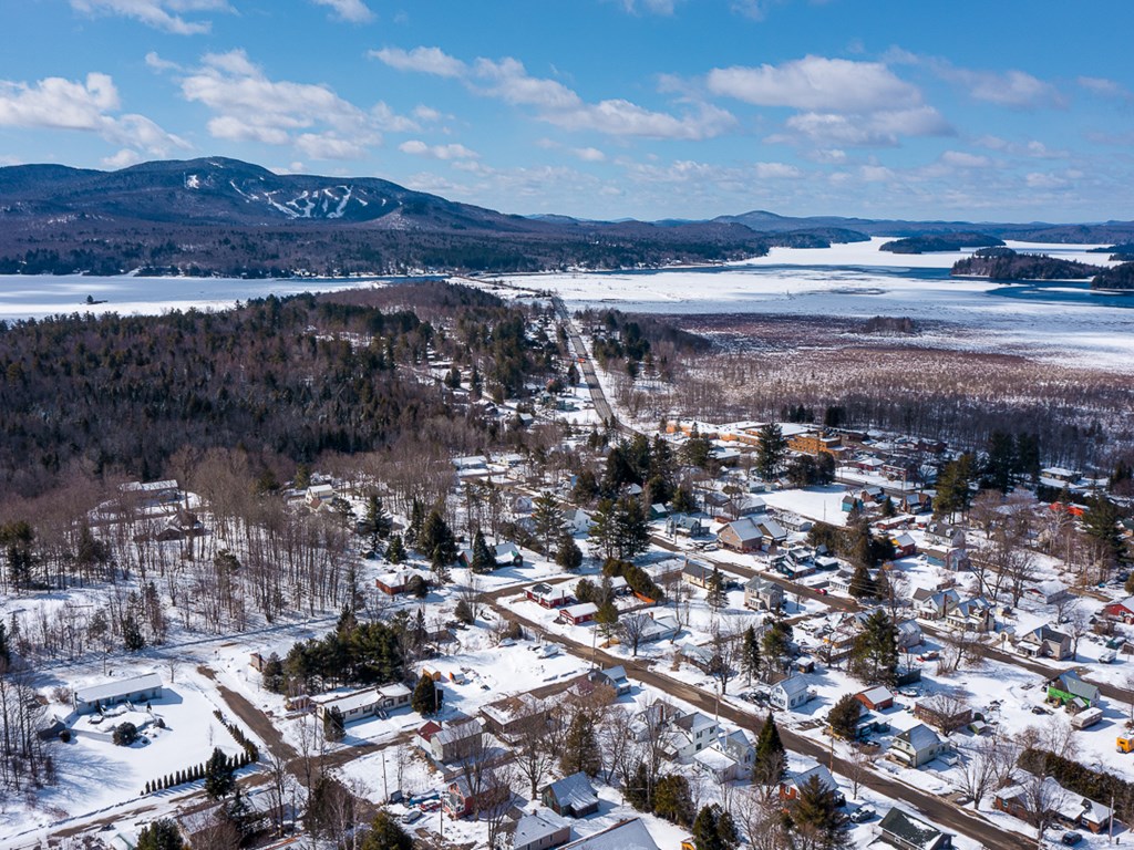 An aerial view of the village of Lake Placid during winter; landscape is flecked with snow and the lake is frozen
