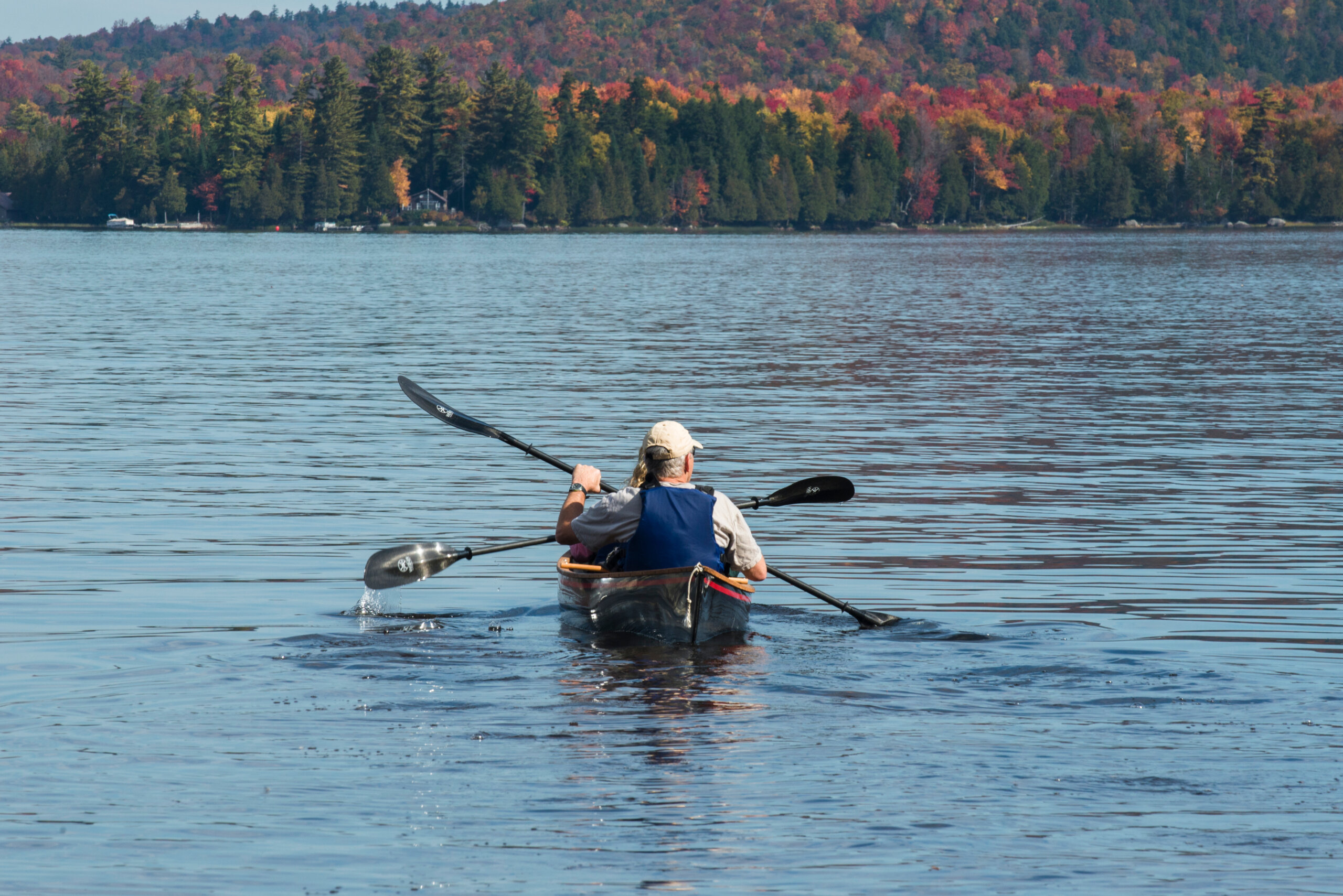 Couple kayaking on a lake in the Adirondacks region of New York during the fall.
